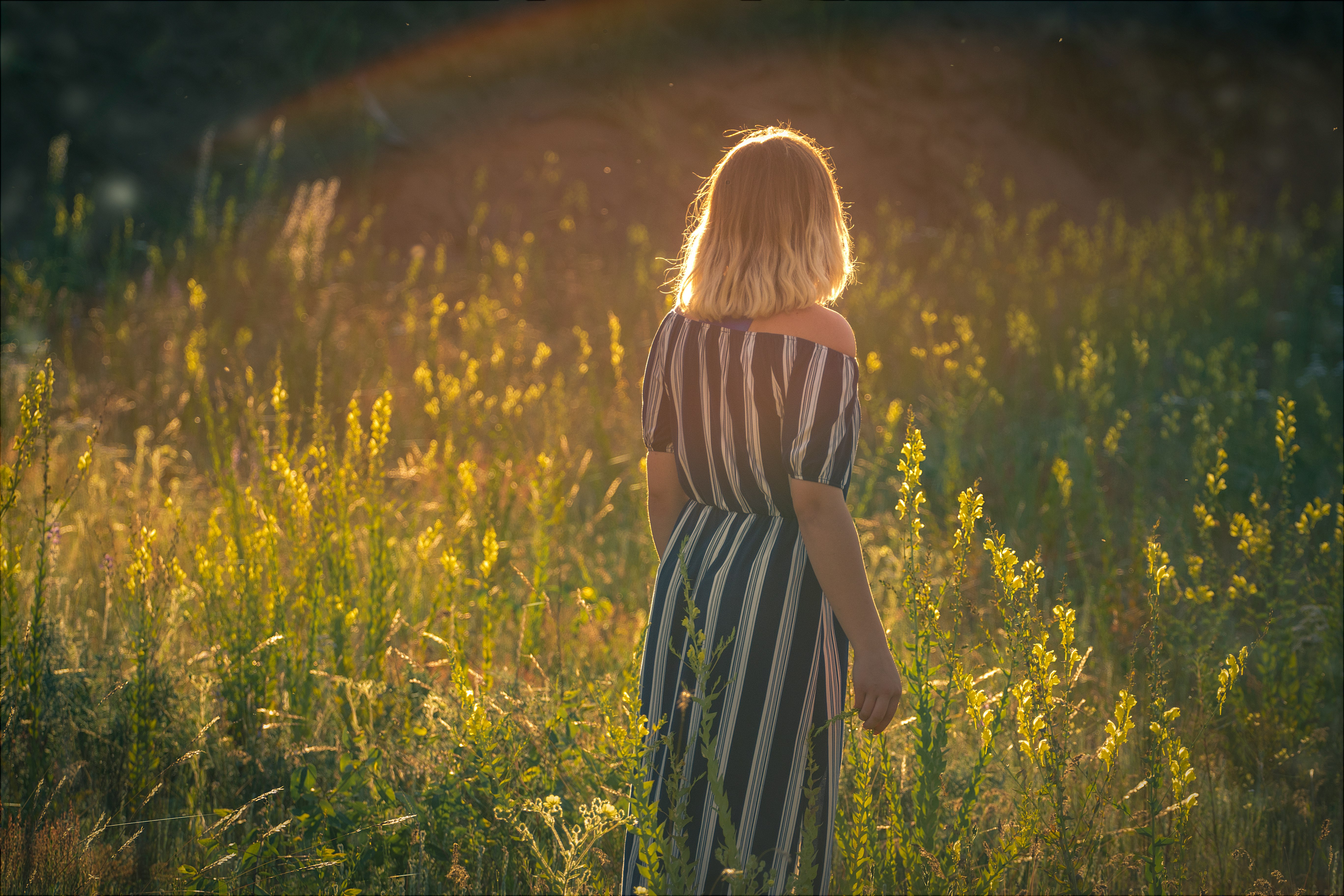 woman in black and white stripe dress standing on green grass field during daytime